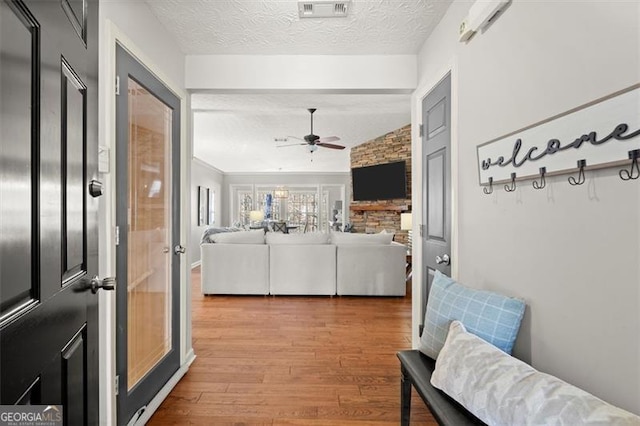 interior space with a textured ceiling, wood finished floors, and visible vents