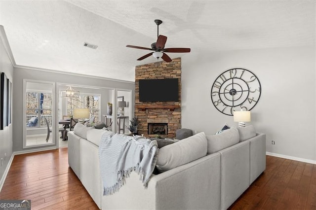 living room with a textured ceiling, dark wood-style flooring, a fireplace, and visible vents