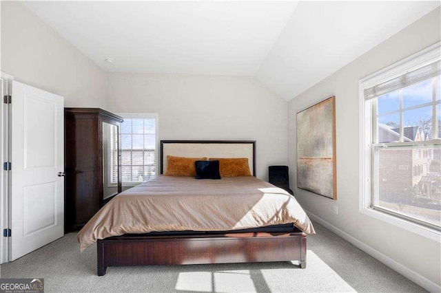 bedroom featuring lofted ceiling, light colored carpet, and baseboards