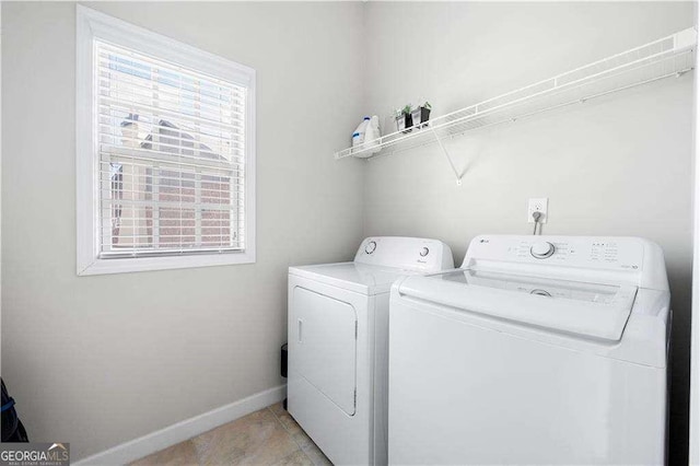 clothes washing area featuring washing machine and dryer, laundry area, light tile patterned flooring, and baseboards