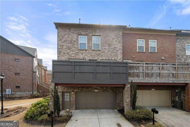 back of property featuring a garage, concrete driveway, and brick siding