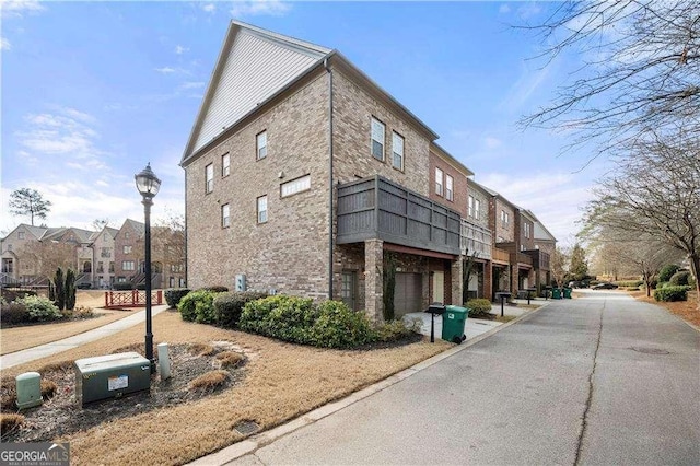 view of building exterior with a garage, a residential view, and aphalt driveway