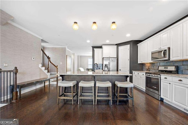 kitchen with a center island with sink, dark wood finished floors, light stone countertops, stainless steel appliances, and white cabinetry