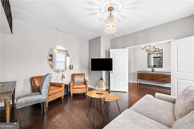 living area featuring arched walkways, dark wood-style flooring, visible vents, baseboards, and an inviting chandelier