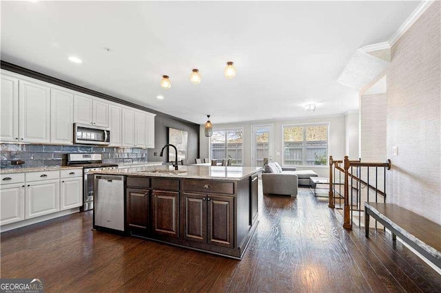 kitchen with a kitchen island with sink, stainless steel appliances, dark wood-type flooring, a sink, and white cabinetry