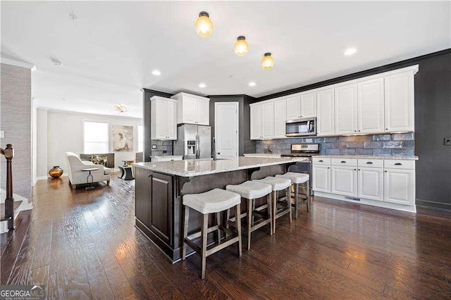 kitchen featuring stainless steel appliances, a breakfast bar area, white cabinetry, and a center island