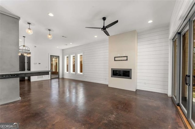 unfurnished living room featuring recessed lighting, concrete floors, ceiling fan with notable chandelier, and a glass covered fireplace