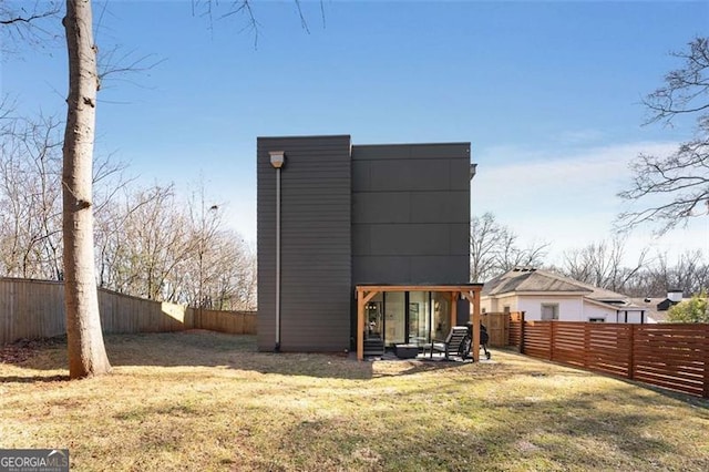 back of house with a fenced backyard and a lawn