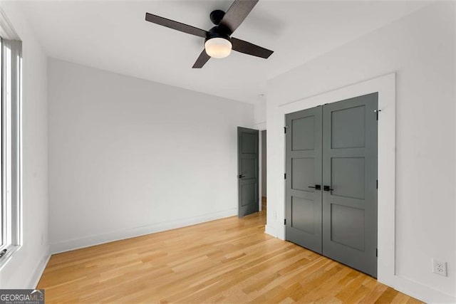 unfurnished bedroom with a closet, wood finished floors, a ceiling fan, and baseboards