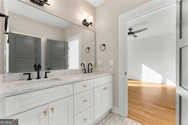 full bath with ceiling fan, double vanity, wood finished floors, and a sink