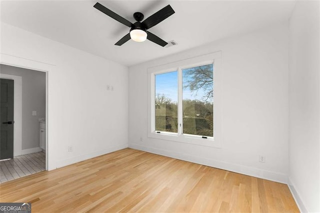 unfurnished room featuring a ceiling fan, baseboards, visible vents, and wood finished floors