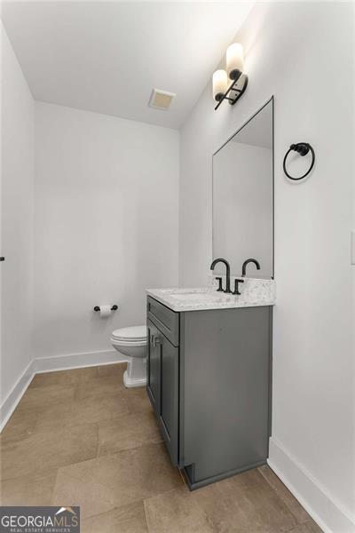 bathroom featuring toilet, visible vents, baseboards, and vanity