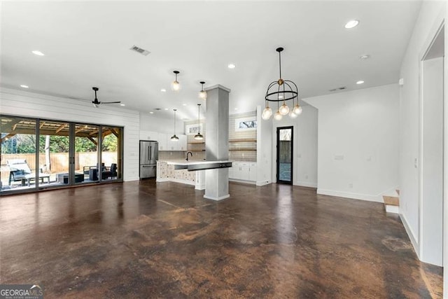 kitchen featuring pendant lighting, freestanding refrigerator, open floor plan, a kitchen island, and a kitchen bar