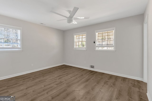 unfurnished room with visible vents, a ceiling fan, baseboards, and wood finished floors