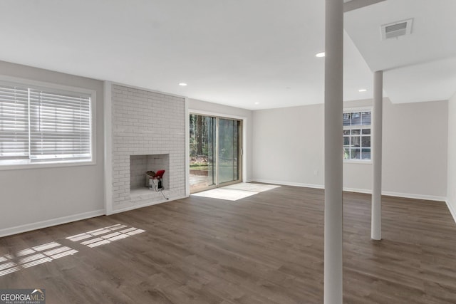 unfurnished living room with visible vents, a fireplace, baseboards, and wood finished floors