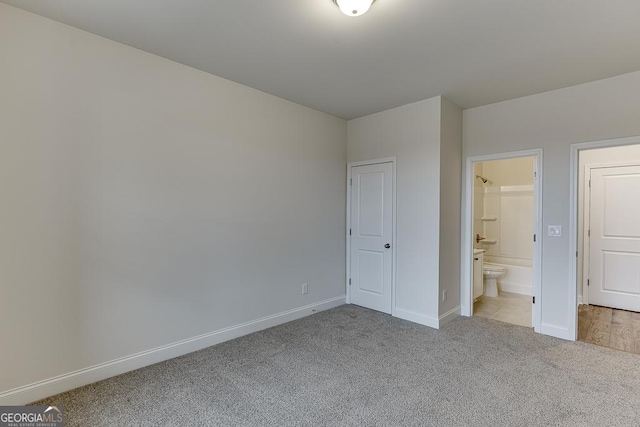 unfurnished bedroom with light carpet, connected bathroom, and baseboards