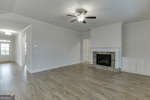 unfurnished living room with crown molding, a stone fireplace, baseboards, and light wood-style floors