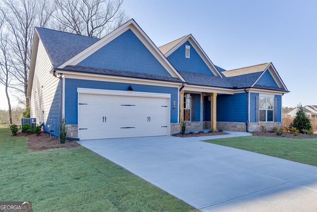 view of front of property with an attached garage, central AC, stone siding, driveway, and a front lawn