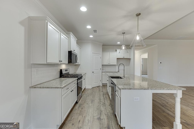 kitchen with decorative light fixtures, a kitchen island with sink, stainless steel appliances, white cabinetry, and a sink