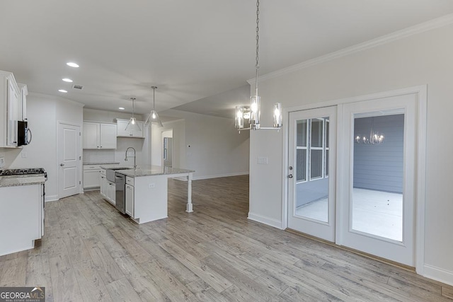 kitchen with pendant lighting, light wood-style floors, a kitchen island with sink, white cabinetry, and dishwasher