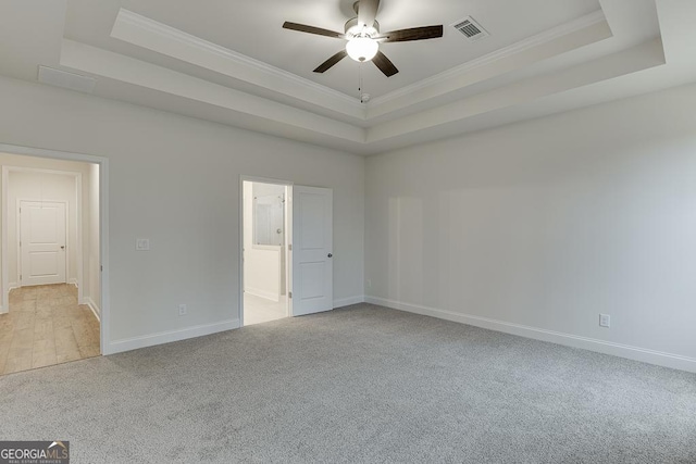 empty room featuring ornamental molding, a raised ceiling, and visible vents