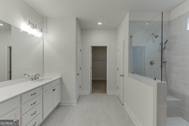 full bathroom with a spacious closet, baseboards, a walk in shower, and vanity