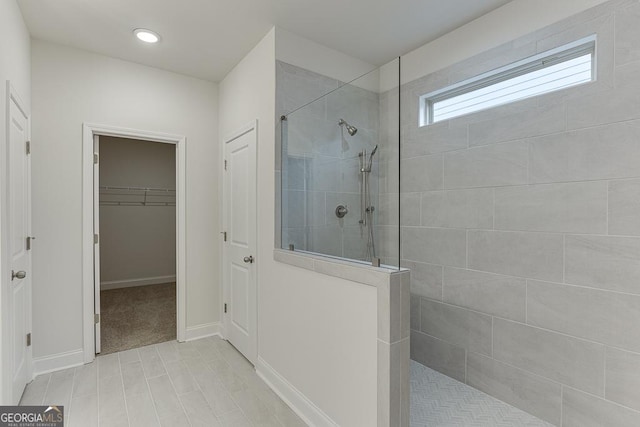 bathroom featuring a walk in closet, baseboards, and a walk in shower