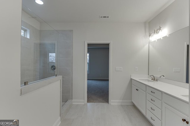 full bathroom featuring double vanity, baseboards, visible vents, walk in shower, and a sink