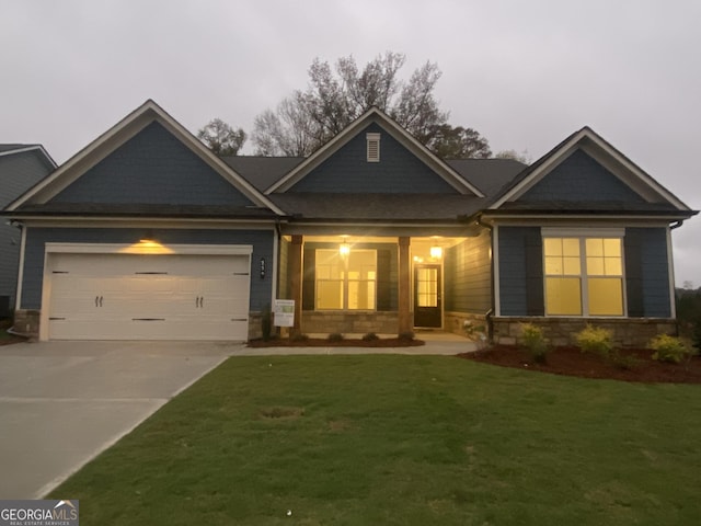 craftsman house with a garage, stone siding, a front lawn, and concrete driveway