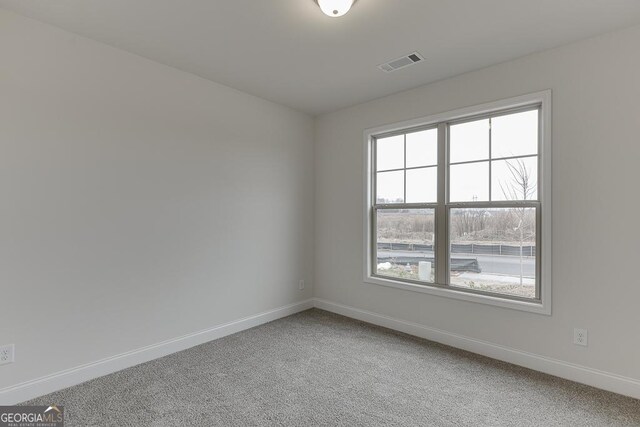 empty room featuring carpet floors, baseboards, and visible vents