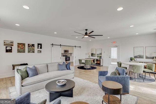 living room featuring a barn door, recessed lighting, and light wood-style floors