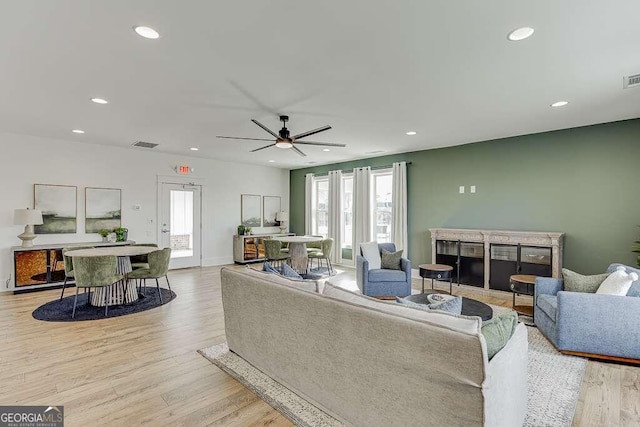 living room featuring baseboards, light wood finished floors, visible vents, and recessed lighting