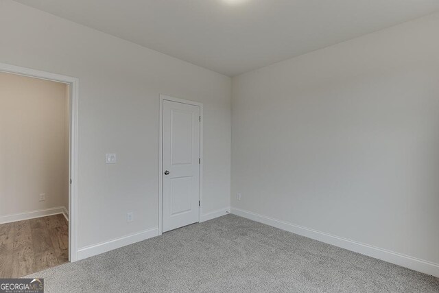 empty room featuring baseboards and light colored carpet