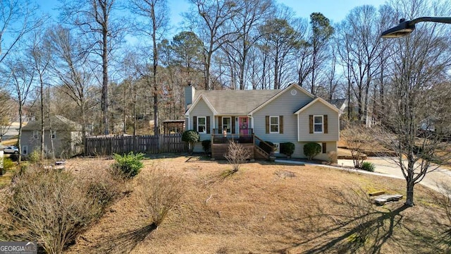 view of front of property with a deck, fence, a chimney, and stairs