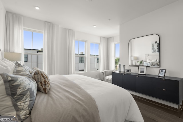 bedroom with radiator heating unit, dark wood-type flooring, and recessed lighting