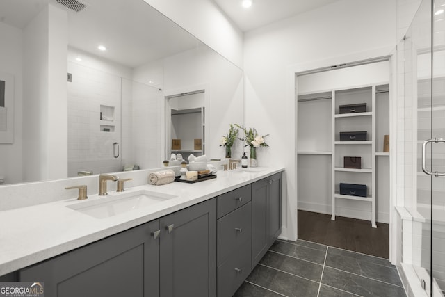 full bath featuring double vanity, a stall shower, a sink, and recessed lighting