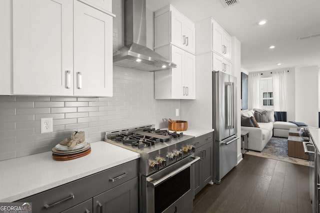 kitchen featuring white cabinets, high end appliances, wall chimney exhaust hood, open floor plan, and light countertops