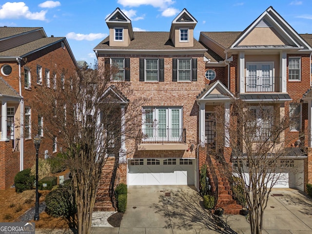 view of front of house featuring a garage, driveway, brick siding, and a balcony