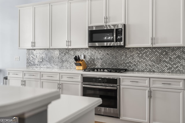 kitchen featuring backsplash, appliances with stainless steel finishes, white cabinets, and light countertops