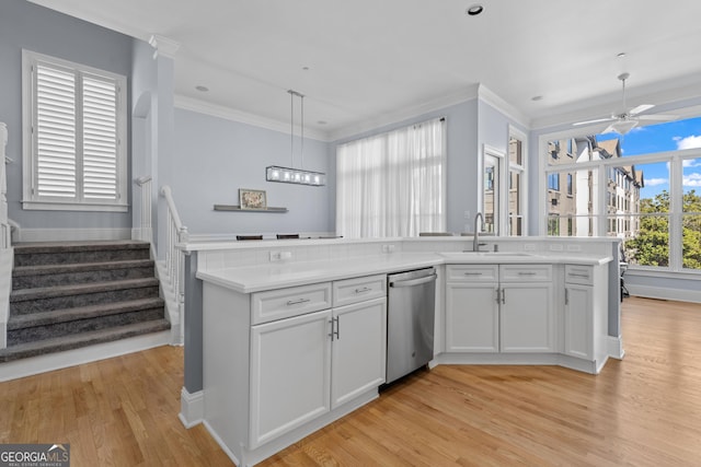 kitchen with light countertops, hanging light fixtures, stainless steel dishwasher, white cabinets, and a sink