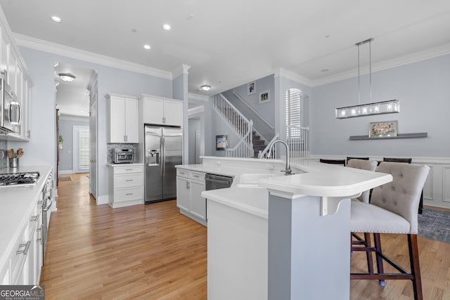 kitchen featuring light countertops, appliances with stainless steel finishes, a sink, and a center island with sink