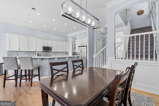 dining space with recessed lighting, a notable chandelier, stairs, ornamental molding, and light wood-type flooring