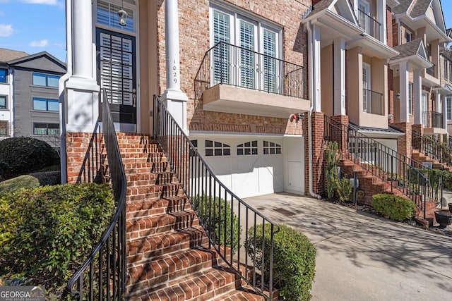 view of front of home with a garage, stairway, concrete driveway, and brick siding