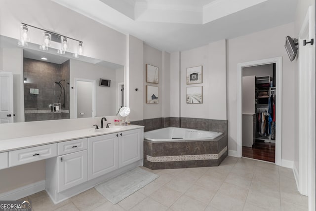 bathroom with tile patterned flooring, vanity, a tile shower, a bath, and a walk in closet