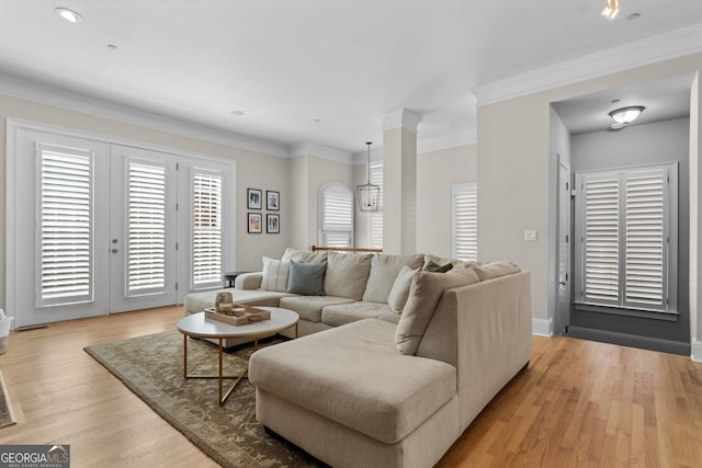 living area with ornamental molding, light wood-type flooring, and baseboards