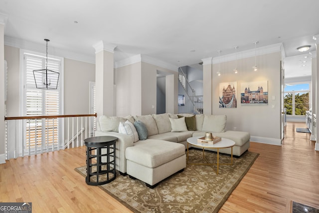 living room with baseboards, ornamental molding, wood finished floors, and a notable chandelier