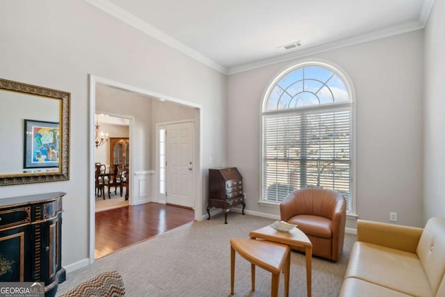 living area featuring a notable chandelier, visible vents, ornamental molding, carpet flooring, and baseboards