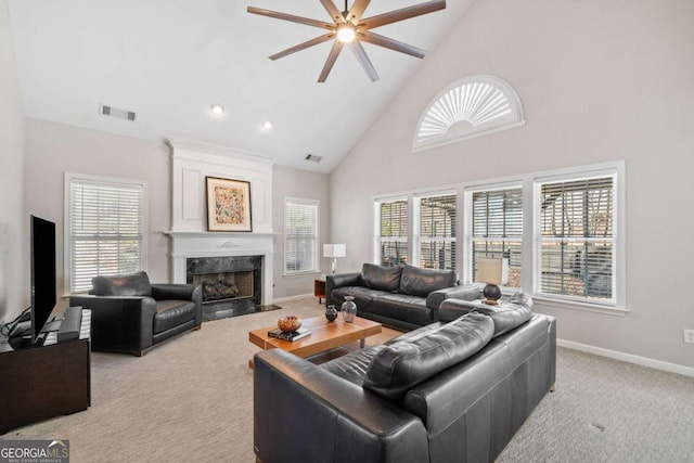 living area featuring light carpet, a premium fireplace, visible vents, and a wealth of natural light