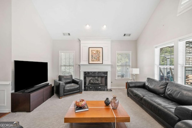 living area with a premium fireplace, carpet flooring, visible vents, and baseboards