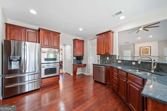 kitchen featuring tasteful backsplash, visible vents, dark stone counters, stainless steel appliances, and a sink